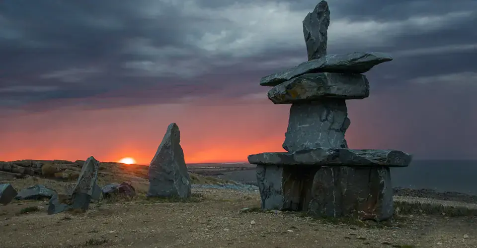 Inukshuk on the Hudson Bay shoreline at sunset near Churchill, Manitoba