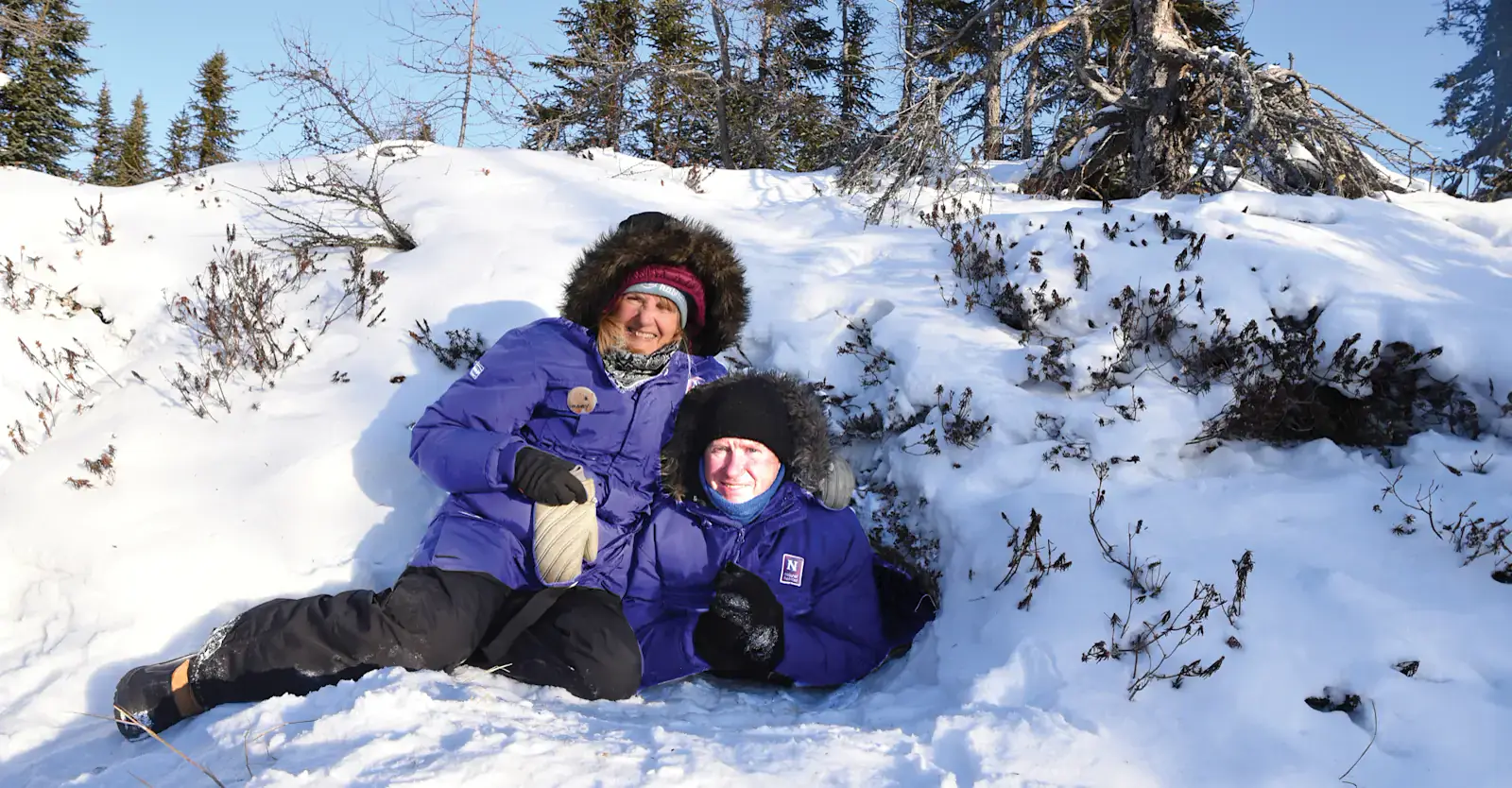 Two travelers sitting at the entrance of a polar bear maternity den site