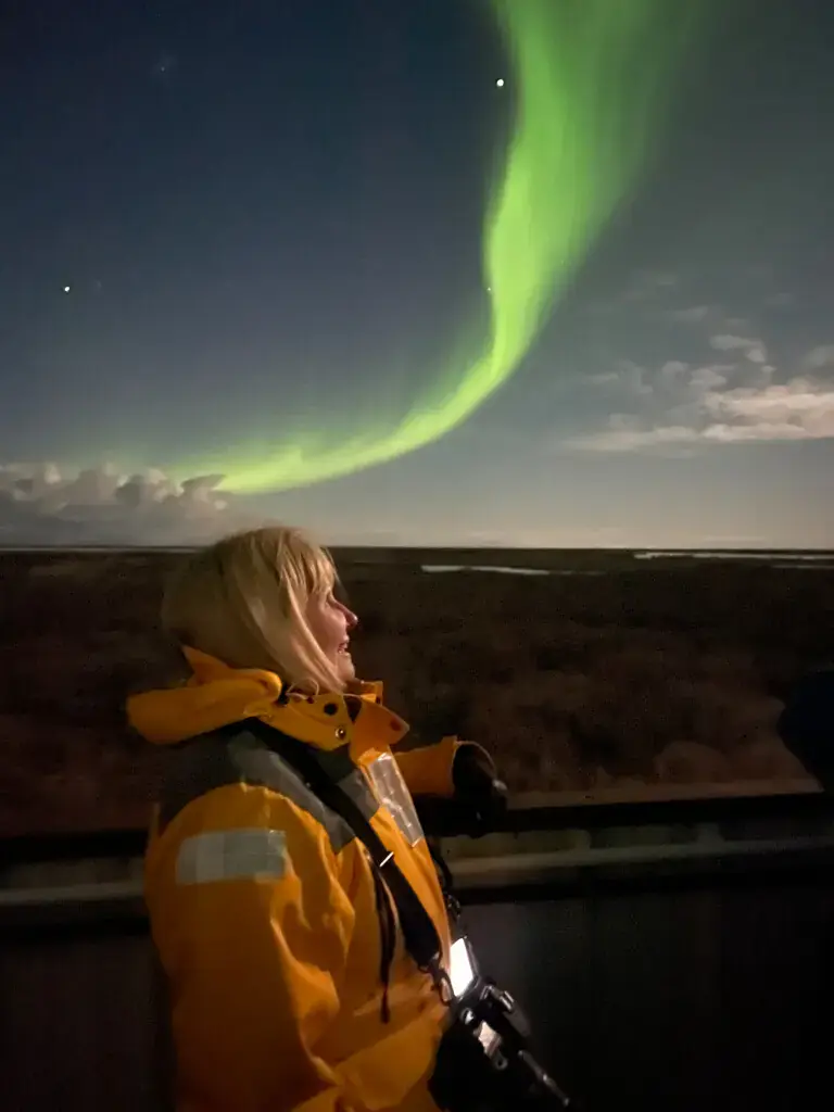 Traveler watching the green aurora borealis from the Tundra Lodge deck